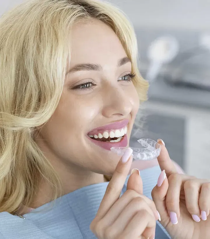 Paciente sonriendo mientras sostiene una férula de ortodoncia invisible